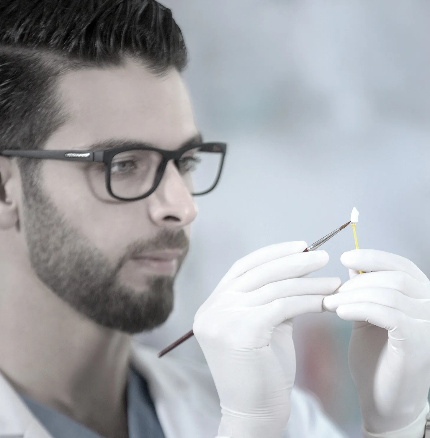 Dr. Mohammed Naji in gloves holding a fine dental instrument