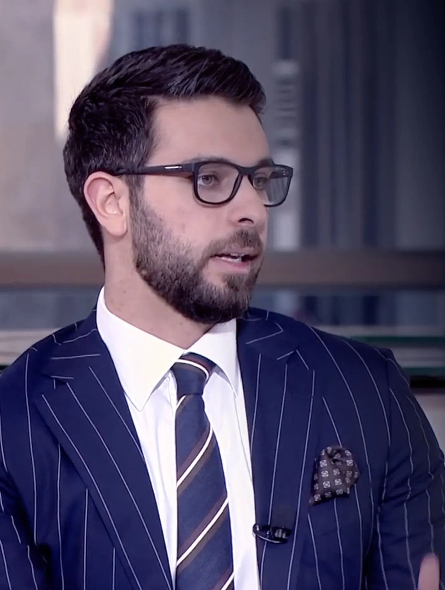 Dr. Mohammed Naji in a pinstripe suit during a television interview